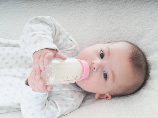 Baby boy  drinking milk from the bottle at home — Stock Photo, Image