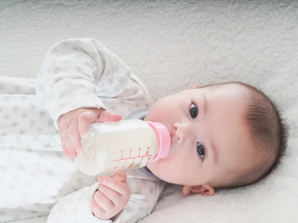 Junge trinkt zu Hause Milch aus der Flasche lizenzfreie Stockfotos