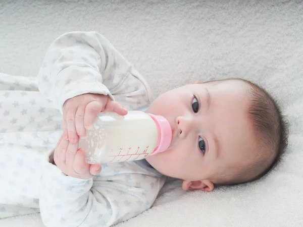 Junge trinkt zu Hause Milch aus der Flasche Stockfoto