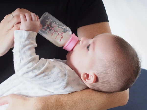 Baby boy dricka mjölk från flaskan hemma Royaltyfria Stockfoton