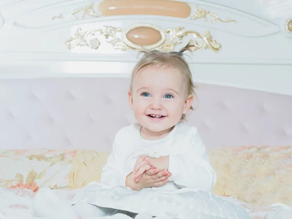 Klein Kaukasische kind meisje, zittend op het bed thuis — Stockfoto