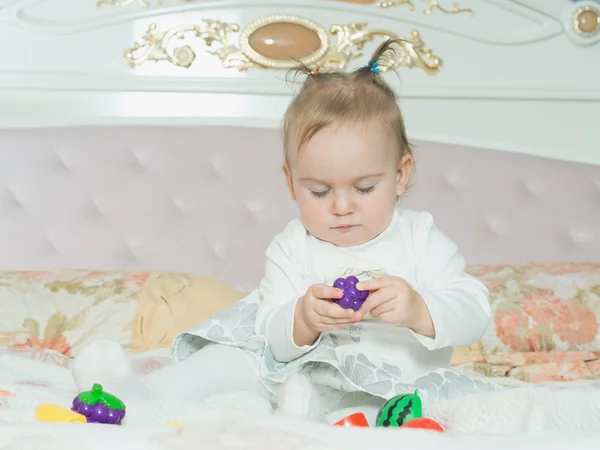 Μικρό παιδί καυκάσιος κορίτσι παίζουν με τα παιχνίδια στο κρεβάτι στο σπίτι — Φωτογραφία Αρχείου