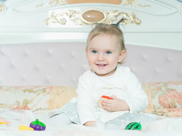 Petite fille caucasienne enfant jouer avec des jouets sur le lit à la maison — Photo