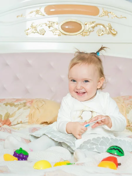 Menina pequena caucasiana brincar com brinquedos na cama em casa — Fotografia de Stock