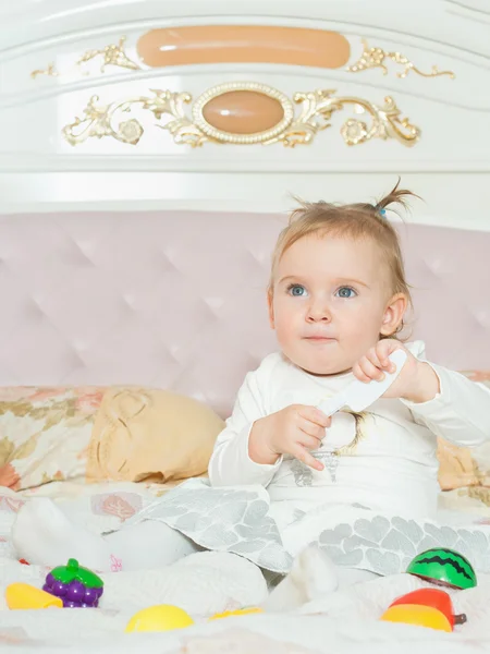 Pequeña niña caucásica jugar con juguetes en la cama en casa —  Fotos de Stock