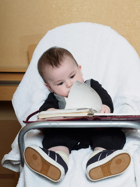 Kleine Kaukasische babyjongen zitten in chear met Kladblok — Stockfoto