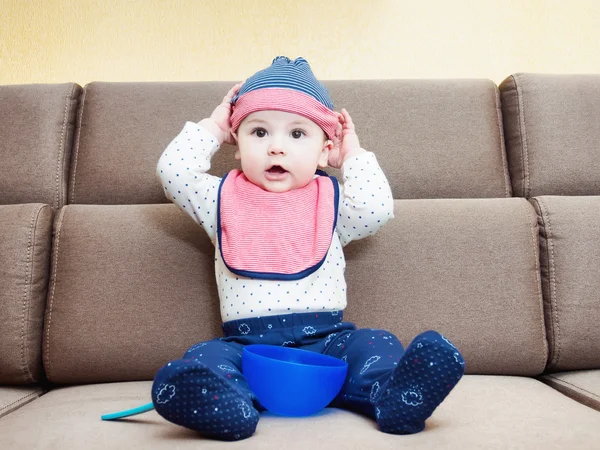 Caucásico bebé niño con babero sentado en el sofá en casa —  Fotos de Stock
