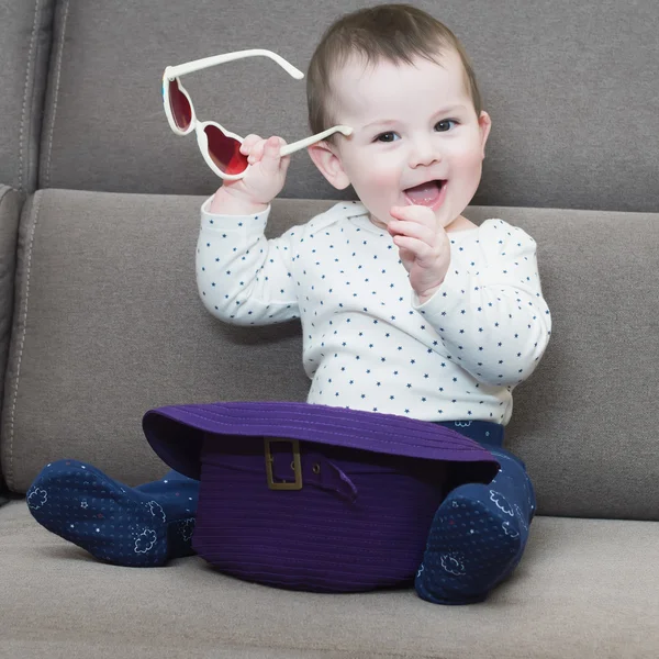 Caucasian baby boy hold glasses  sitting on sofa at home — Stock Photo, Image