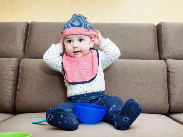 Caucásico bebé niño con babero sentado en el sofá en casa —  Fotos de Stock