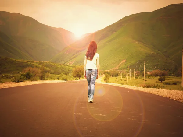 Gün batımında dağlara yolda yürüyen küçük kız çocuğu — Stok fotoğraf