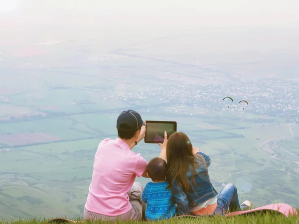 Portrait of family mother taking photo paraglider with brother and sister together sitting in nature — Stock Photo, Image