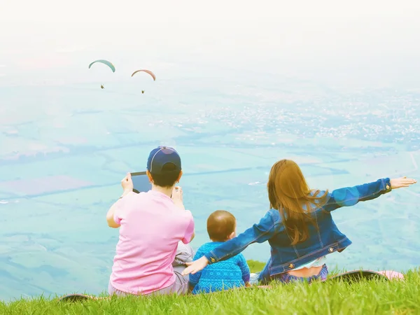 Portrait of family mother taking photo paraglider with brother and sister together sitting in nature — Stock Photo, Image