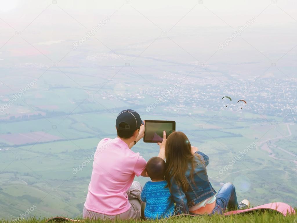 Portrait of family mother taking photo paraglider with brother and sister together sitting in nature