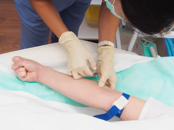 Врач берет кровь с руки пациентки для обследования — стоковое фото