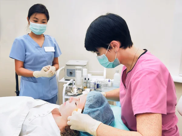 Kosmetologi förfarande föryngring, vitalisering, hud näring. Läkare med sjuksköterskan att göra mask av skönhet grädde. — Stockfoto