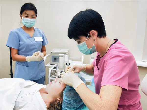 Procedimiento de cosmetología rejuvenecimiento, revitalización, nutrición de la piel. Médico con enfermera haciendo máscara de crema de belleza . — Foto de Stock