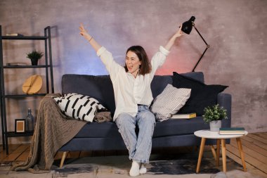 Asyalı kadın kanepede oturmuş televizyon izliyor ve çok komik.