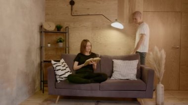 Genç çift rahat evlerinde dinleniyor. Kitap okuyan kız.