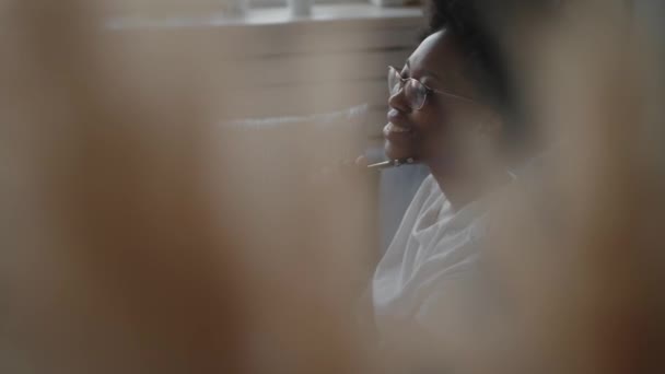 Chica afroamericana escribe en un cuaderno en una habitación acogedora — Vídeos de Stock
