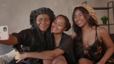 Kanepede oturan üç pozitif Afrikalı Amerikalı kız telefonda fotoğraflandı.