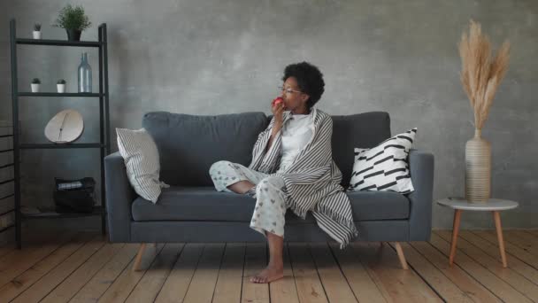 Boldog afro-amerikai fiatal nő ül pihenni kényelmes kanapén, és boldog az üzenetet a telefonon — Stock videók