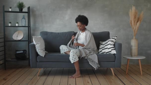 Feliz afroamericana joven mujer sentarse relajarse en acogedor sofá feliz de mudarse a un nuevo apartamento. Sonriente negro chica resto en cómodo sofá en sala de estar soñando — Vídeos de Stock