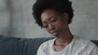 Afro-Amerikalı kız rahat bir odada deftere yazıyor.