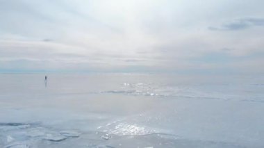 Baykal Gölü. Genç bir fotoğrafçı buzda yürüyor manzaranın tadını çıkarıyor ve fotoğraf çekiyor..