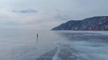 Baykal Gölü. Genç bir fotoğrafçı buzda yürüyor manzaranın tadını çıkarıyor ve fotoğraf çekiyor..