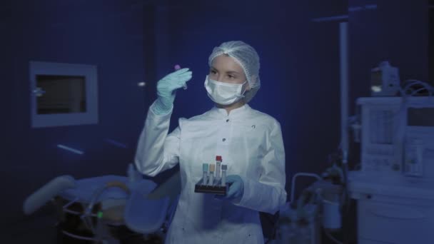 Portrait of Young Female Doctor in Medical Mask Looking at Camera. The doctor Holds the Cones in his Hands — Stock Video