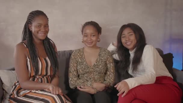 Three African girls are sitting on the couch and looking at the camera. Body positive — Stock Video