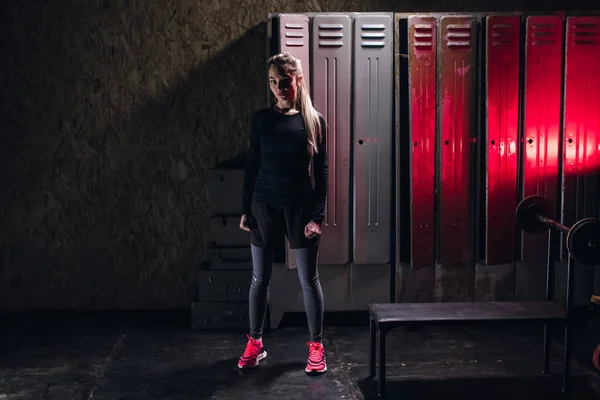 Young girl stands in an atmospheric fitness room against the background of lockers for changing room Stock Picture