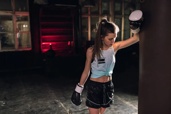 cool female fighter in boxing gloves trains in the gym. Mixed martial arts