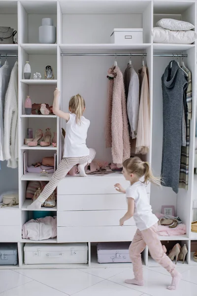 Twin Girls essayer sur les choses dans leurs mères vestiaire moderne. — Photo