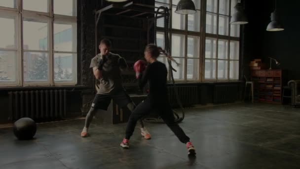 Боксёры девушка и мужчина спаррингуют в спортзале — стоковое видео