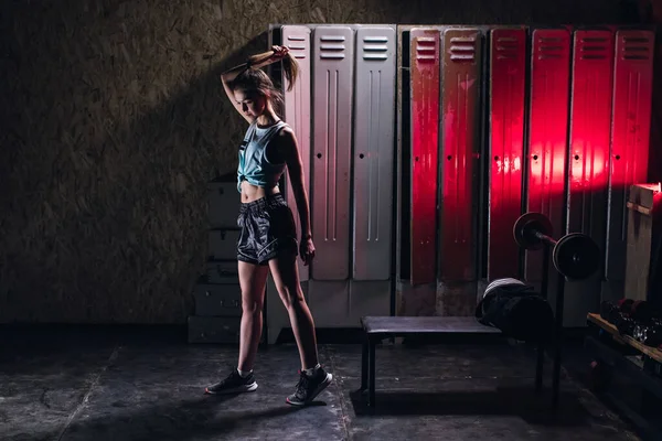Fiatal lány áll egy atmoszférikus fitness terem hátterében szekrények öltözőben — Stock Fotó
