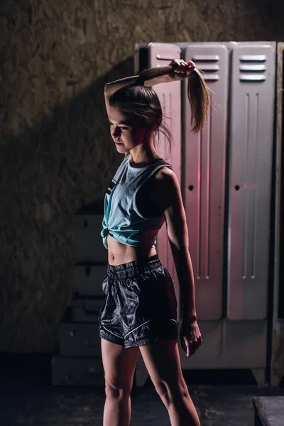 Fiatal lány áll egy atmoszférikus fitness terem hátterében szekrények öltözőben — Stock Fotó