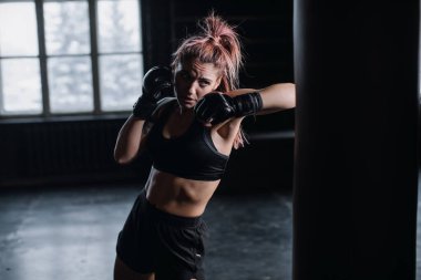 Boks eldivenli havalı kadın boksör spor salonunda antrenman yapıyor. Karışık dövüş sanatları