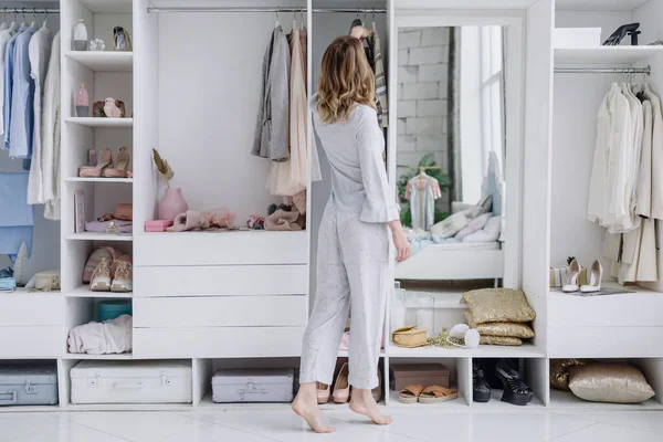 Young woman chooses a dress in her modern dressing room Royalty Free Stock Images