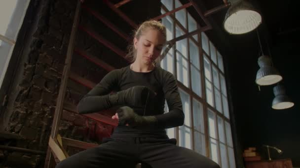 소녀 투사는 체육관에서 훈련하기 전에 손을 붕대로 감는다. 붉은 네온 빛 — 비디오