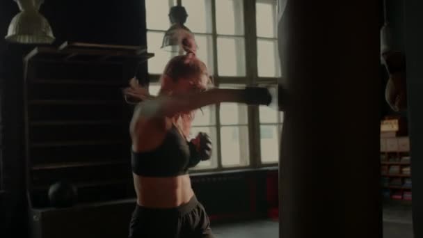 4k video de luchadora atlética ejercitándose con saco de boxeo en el gimnasio durante el entrenamiento de kickboxing y defensa personal — Vídeo de stock