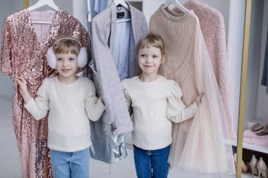 Genç anne modern bir soyunma odasında oturuyor ve ikiz kızlarıyla selfie çekiyor.