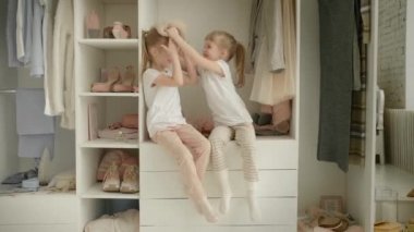 Aile gardırobu. Mutlu ikiz kardeşler dolapta doğal organik giysilerle rahat soyunma odasında neşeyle oynuyorlar.