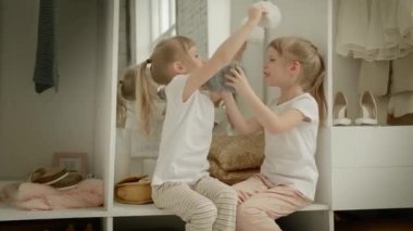 Aile gardırobu. Mutlu ikiz kardeşler dolapta doğal organik giysilerle rahat soyunma odasında neşeyle oynuyorlar.
