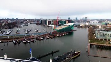 Amsterdam Merkez Havayolları zaman göstergesi, Amsterdam 'daki şehir merkezi ve Lj nehri, Hollanda feribotları ve toplu taşıma araçları insansız hava aracı görüntüsü üzerinden uçuyor..