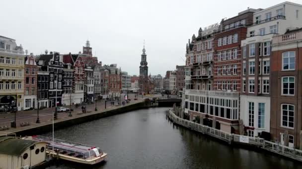 Amsterdam, Kuzey Hollanda, Hollanda - 16-01-2021 The Munttoren in the city center. Hava aracı Amstel nehrinin üzerinde uçuyor.. — Stok video