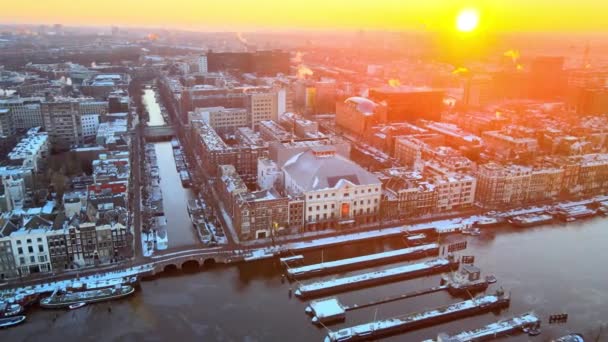 Amsterdam, Kuzey Hollanda, Hollanda - 13-02-2021. Magerebrug ve Carre Theather. Güneşli bir kış gününde, güneş doğarken Amstel Nehri 'nin üstünde.. — Stok video