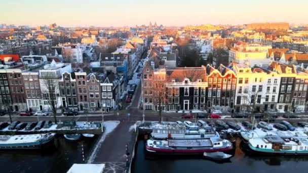 Amszterdam, Észak-Hollandia, Hollandia - 2021. Csatornaházak az Amstel folyó mentén. Napkelte egy hideg téli napon. — Stock videók