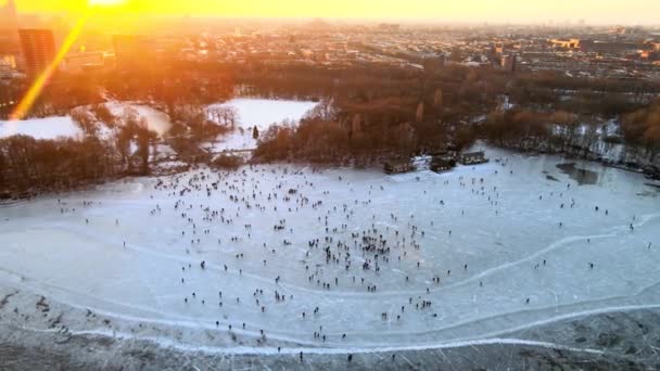 Aerial view of a large crowd of people ice skating near the Flevopark on a frozen lake in Amsterdam, The Netherlands. — Stock Video