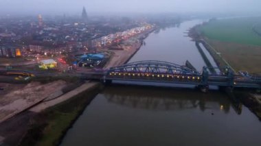 Zutphen, Overijssel, Hollanda - 2-1-2021 Oude IJsselbrug in Zutphen. Gün batımında Ijsel nehrinden geçen demiryolu ve arabalar. Hızlandırılmış zaman ayarlı dron görüntüsü.